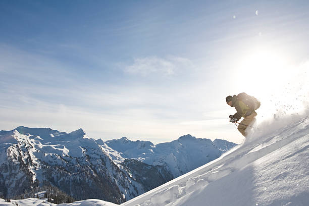 A skier descends. A solo skier descends down a mountain in the British Columbia backcountry. revelstoke stock pictures, royalty-free photos & images