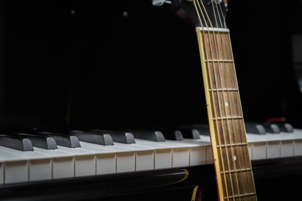 istock acoustic guitar against grand piano keys 852809352
