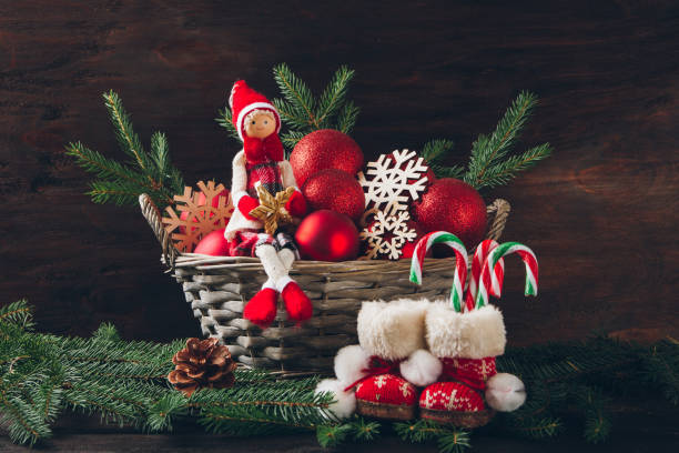 istock Doll sitting in a basket with fir tree branches, red balls and s 852835002