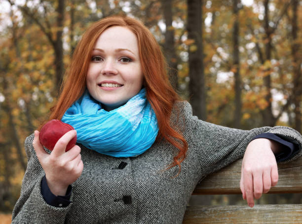 giovane donna con mela nel parco autunnale, foglie gialle e alberi - bench sitting tree apple foto e immagini stock