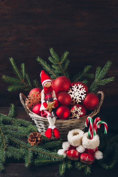 istock Doll sitting in a basket with fir tree branches, red balls and s 852843870