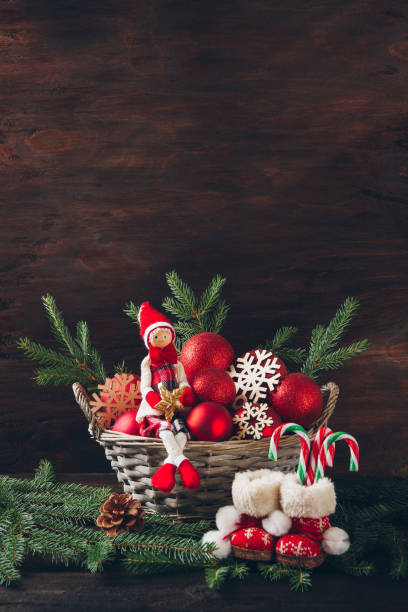 istock Doll sitting in a basket with fir tree branches, red balls and s 852845144