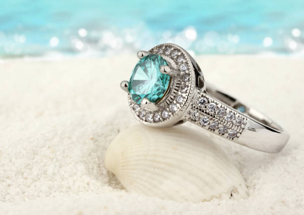 Jewelry ring with aquamarine gem on sand beach background Jewelry ring with aquamarine gem on sand beach background gem jewelry gold glamour stock pictures, royalty-free photos & images