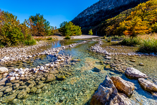 Bright Beautiful Fall Foliage Lining the Rocky Riverbed of the Crystal Clear Frio River at Garner State Park, Texas..