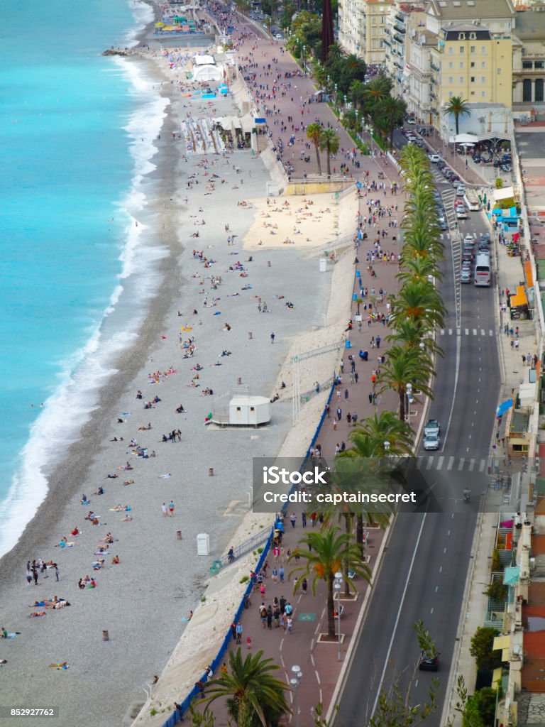Aerial shot of Promenade des Anglais in Nice, France Shot from Parc du Mont Boron, the scene far below shows the many tourists and locals strolling the Promenade des Anglais as the bright blue Mediterranean sea laps at the shore. Aerial View Stock Photo