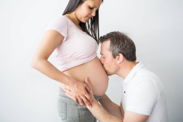 istock Happy pregnant woman with the husband in studio on grey 852935528