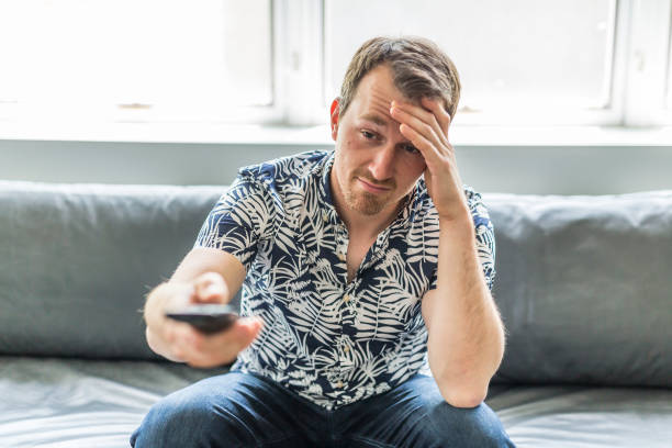 istock Bored man watching tv and zapping sitting on a couch at home 852938220