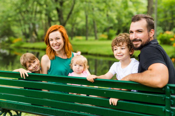 istock Happy family sitting on bench in park 852960618