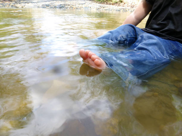 Toddler sitting in creek with toes peeking above the water