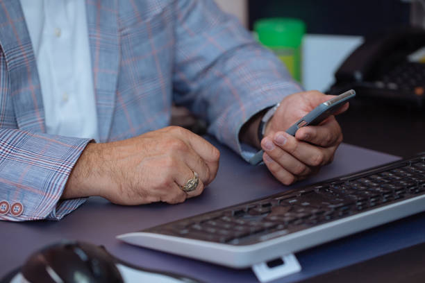 istock Close-up hands of businessman using mobile phone at office. 853102366