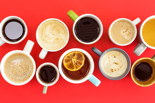 Different cups of coffee on red background