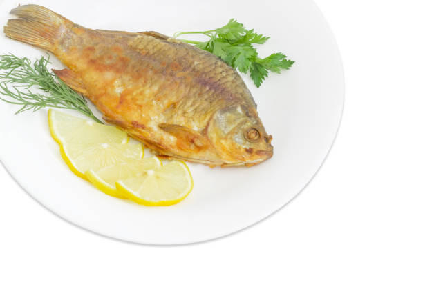 istock Fried crucian with lemon and potherb on white dish 853116198