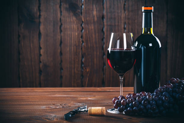 бутылка и стакан красного вина, винограда и пробки на деревянном фоне. - wine wine bottle cellar grape стоковые фото и изображения