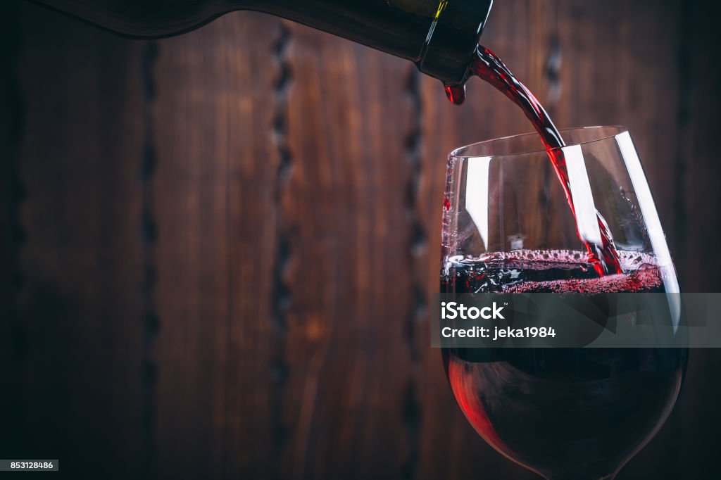 Pouring red wine into the glass against wooden background Wine Stock Photo