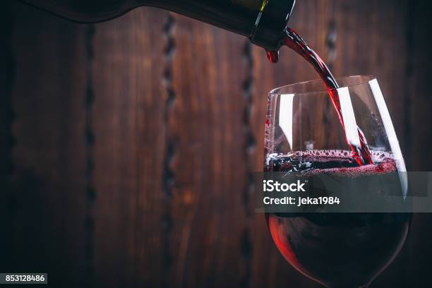 Foto de Servindo O Vinho Tinto Em Vidro Contra Fundo De Madeira e mais fotos de stock de Vinho
