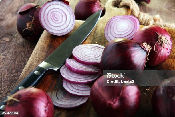 Red Onions Circles And Red Onions On Board Against Wooden Background Stock Photo - Download Image Now