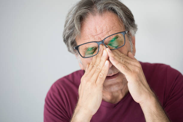Old man with eye fatigue stock photo