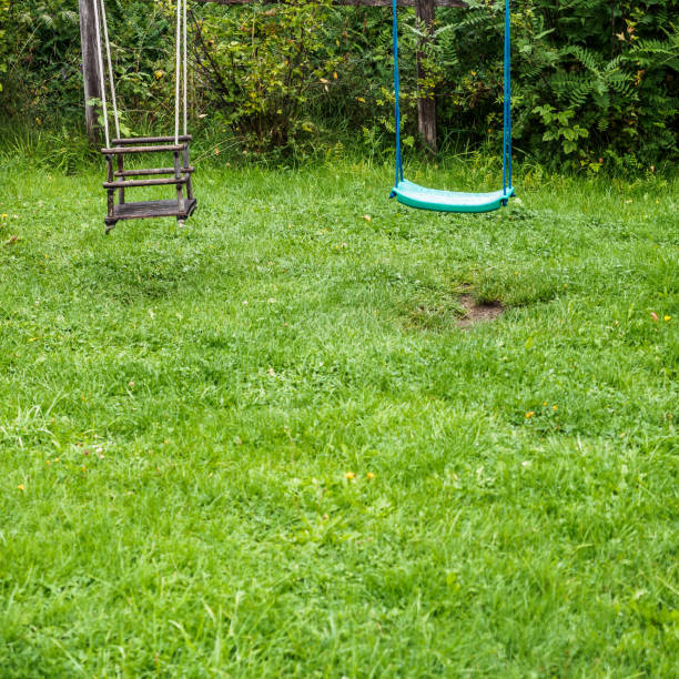 Two childrens's swings in a garden on a rainy day. Photograph taken in Krakaudorf, Styria, Austria.