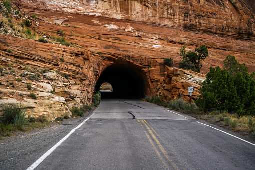 A tunnel through one of the red rock mountains looks like someone just drilled it.