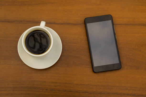 istock Cup of coffee and smartphone on wooden table. Top view 853186176