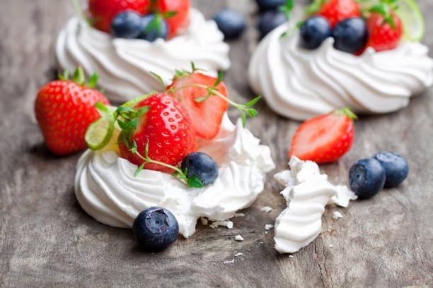 istock Mini  Pavlova meringue cakes with berries and lime on rustic wooden background 853192202