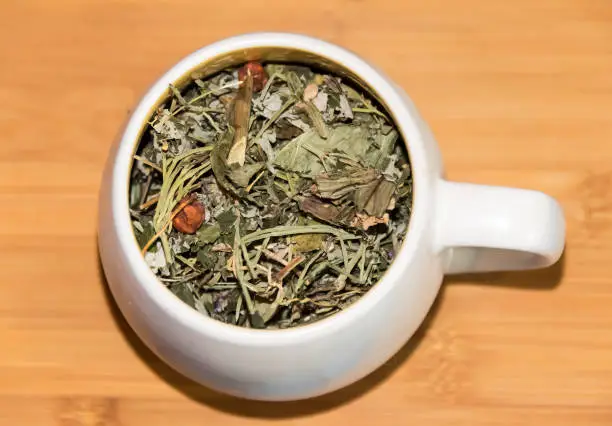 cup with dry green herbal tea on  wooden background