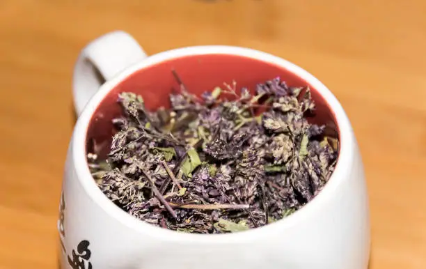 cup with dry green herbal tea on  wooden background