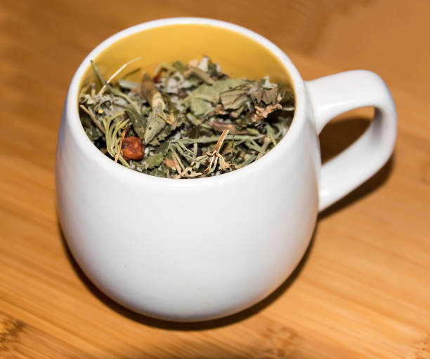cup with dry green herbal tea on  wooden background