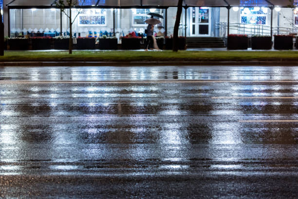 people walking on pavement during rain at night. blurred view.