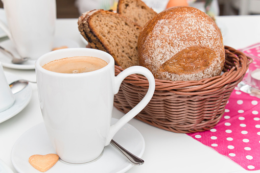 Cup of coffee crema and a basket with bread and buns