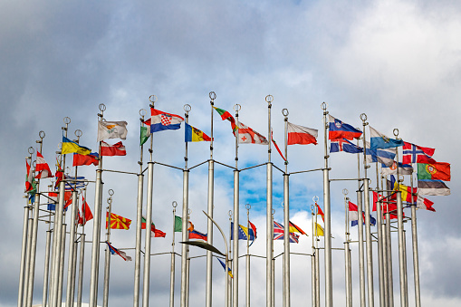 Flags of different countries on cloudy sky background