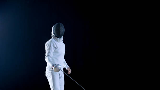 istock Fully Equipped Skilled Fencer Training with a Foil. He Practices Attack, defense,  Leap, Thrust and Lunge. Shot Isolated on Black Background. 853236736