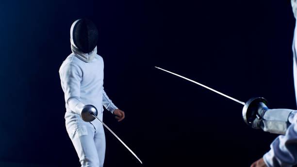 istock Two Professional Fully Equipped Fencers Fight with Foils. They Attack, Defend, Leap, Thrust and Lunge. Shot Isolated on Black Background. 853236800