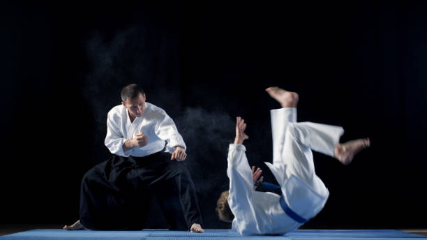 istock Martial Arts Master Wearing Hakamas Teaches Young Student Aikido Technique of Throwing over the Shoulder Shot Isolated on Black Background. 853236808