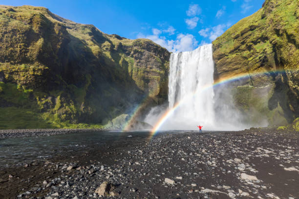 istock Man dressed standing at the base of Skogafoss waterfall 853248856