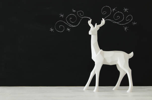 istock White reindeer on wooden table over chalkboard background whith hand drawn chalk illustrations 853252342