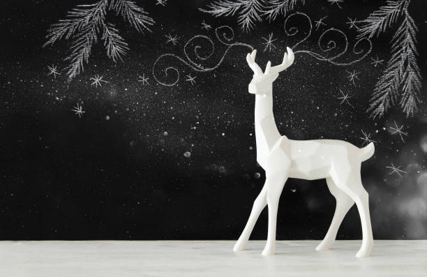 istock White reindeer on wooden table over chalkboard background whith hand drawn chalk illustrations 853252360
