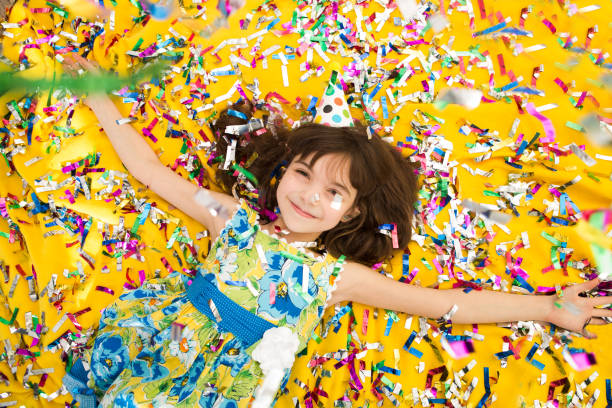 szczęśliwe dziecko świętuje imprezę z dmuchającym konfetti z góry. dziewczyna na imprezie urodzinowej.  pozytywne emocje. - kids birthday party zdjęcia i obrazy z banku zdjęć