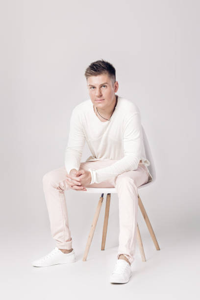 istock handsome young man in white sweater sits on a chair on 853271584