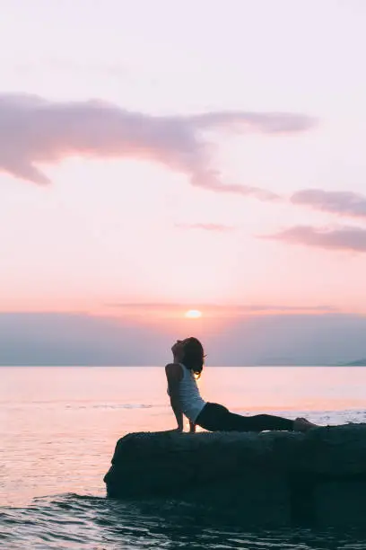 Photo of Young woman doing yoga by the sea