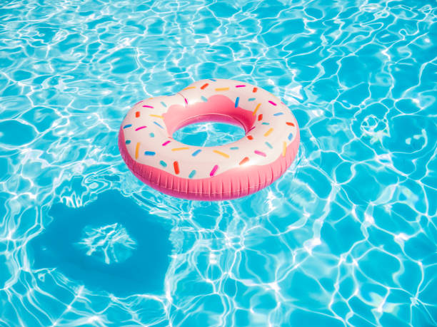 rosa aufblasbaren donut schwimmen ring in einem schwimmbad - float stock-fotos und bilder