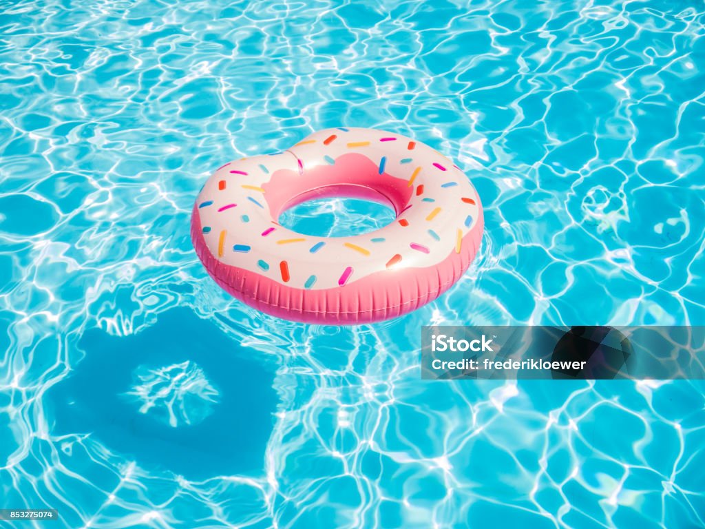 Pink inflatable donut swimming ring in a swimming pool Swimming Pool Stock Photo