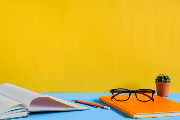 istock Books Pencil and glasses on a blue wooden table 853278448