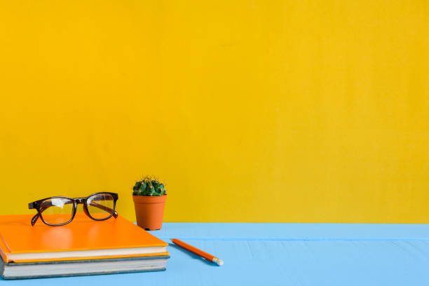 istock Books Pencil and glasses on a blue wooden table 853278470