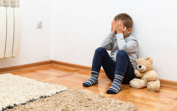 istock Sad boy is sitting on the floor with his hands on his face 853284670