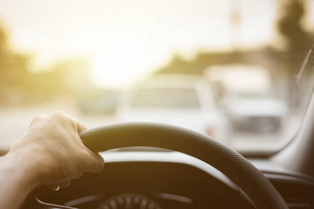 istock Man hands holding steering driving car on the road and traffic background 853285120