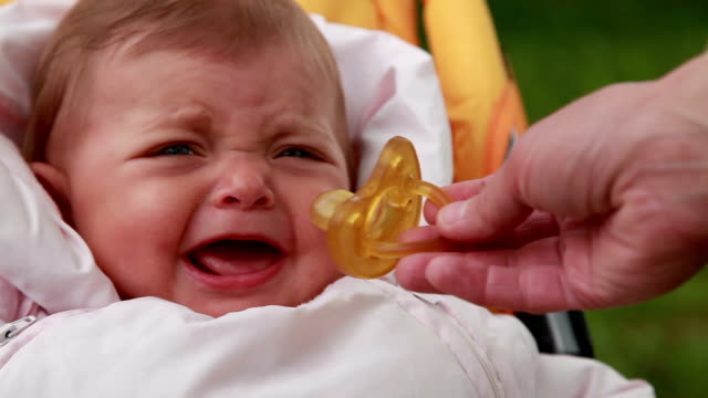 Close-up of a mothers hand giving pacifier to a baby