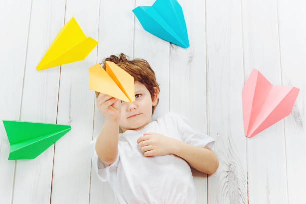 istock Happy laughing child throwing paper airplane indoors. 853287812