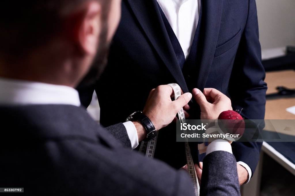 Fitting Suit to Model Over shoulder view of bearded fashion designer fitting bespoke suit to model, close-up shot Tailor Stock Photo