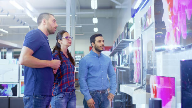 istock In the Electronics Store Professional Consultant Approaches Young Couple with His Expert Advice on Which of New Models of 4K TV's is Best for Their Home and Budget. 853324188